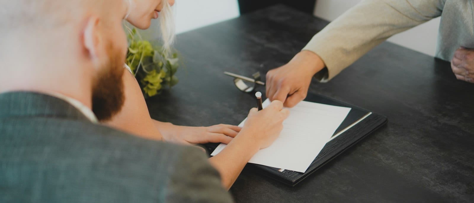 Pareja firmando documentos en un escritorio